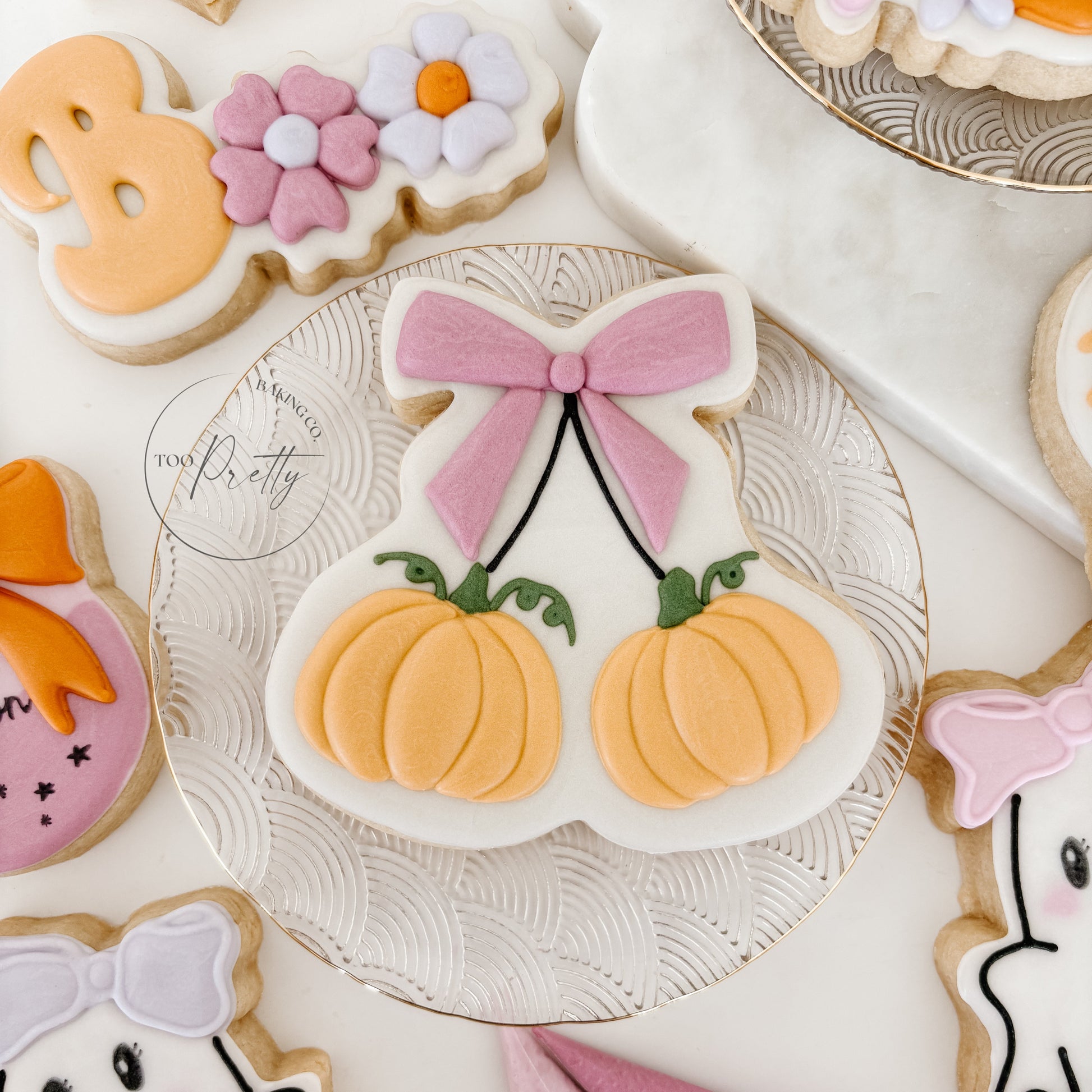 Decorative cookies including pumpkins, flowers, and ghosts on a white surface.