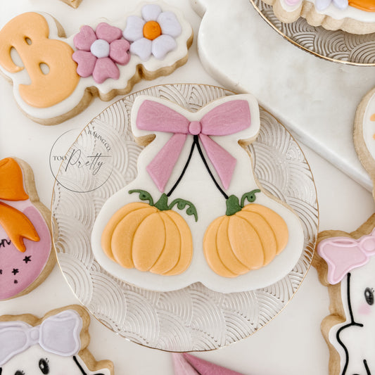 Decorative cookies including pumpkins, flowers, and ghosts on a white surface.