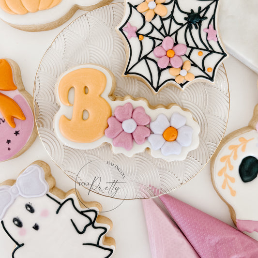 decorated halloween cookie that says "boo" with floral details.