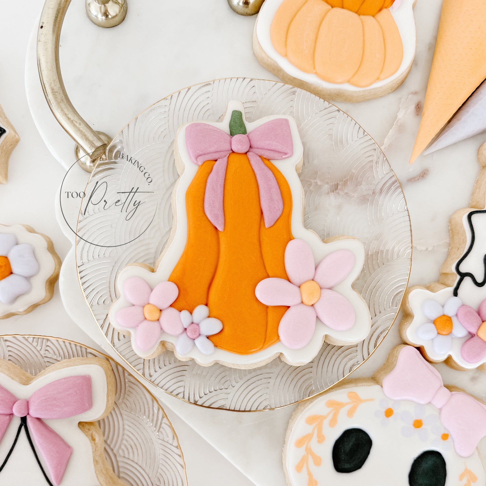 decorated halloween cookie of a pumpkin with bow and floral detail.