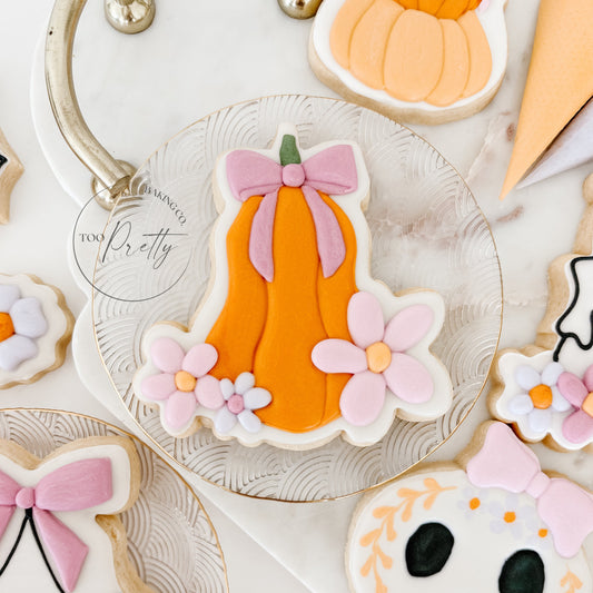 decorated halloween cookie of a pumpkin with bow and floral detail.