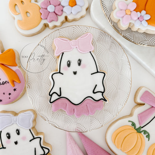 decorated cookie with girlie ghost wearing a dress and bow on her head.