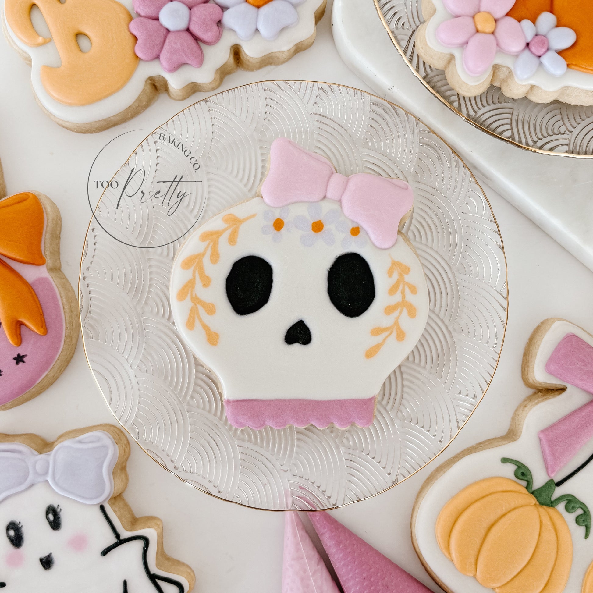 Decorative cookies shaped like a skull, ghost, and pumpkins on a white surface.
