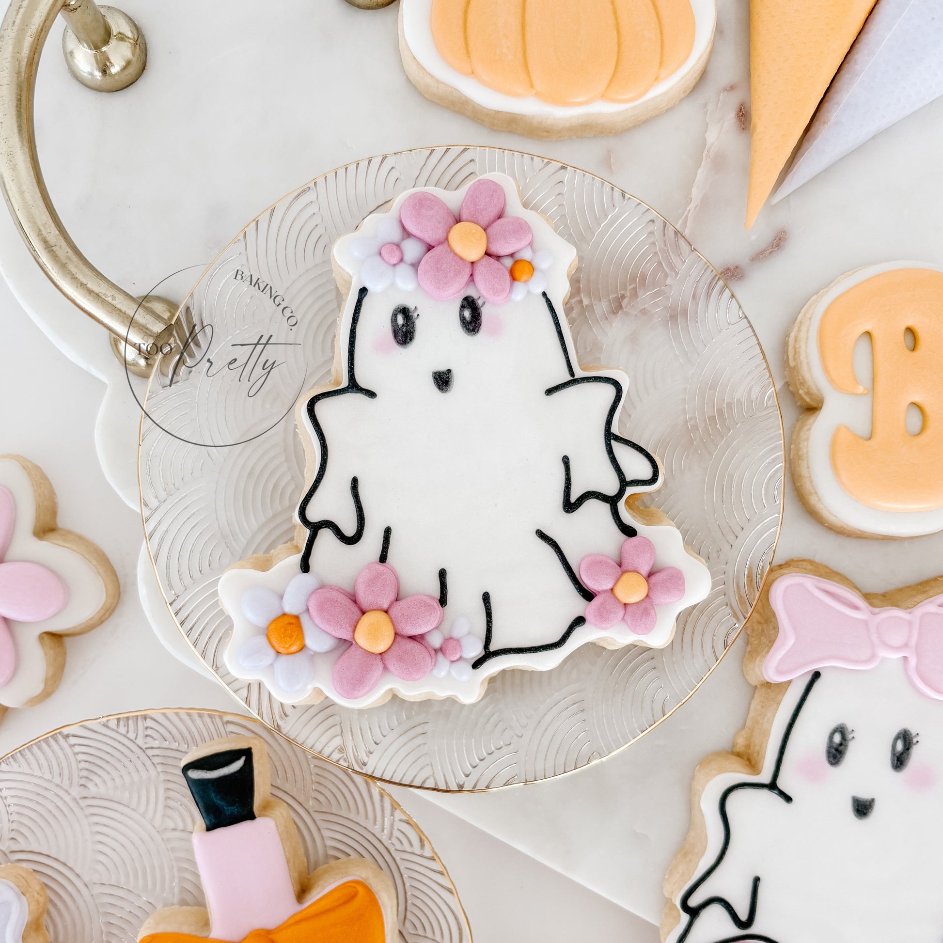 Decorative cookies shaped like a ghost, potion bottle, and pumpkins on a white surface.