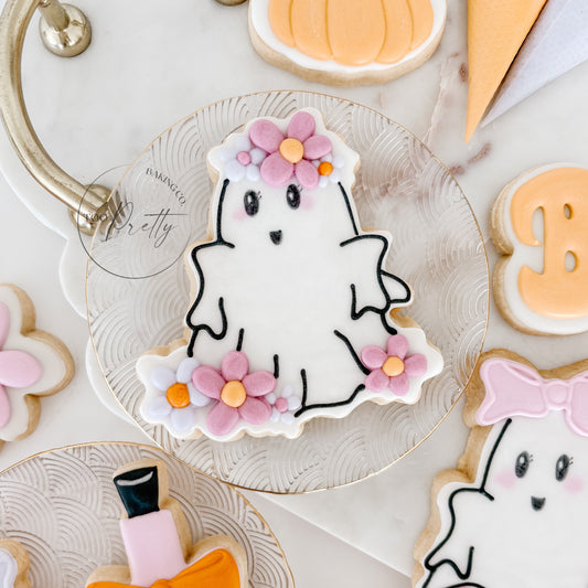 Decorative cookies shaped like a ghost, potion bottle, and pumpkins on a white surface.