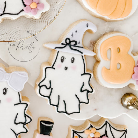 Decorative cookies shaped like ghosts, and pumpkins on a white surface.